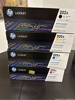 Stack of four HP LaserJet 202A toner cartridge boxes: black, cyan, yellow, magenta
