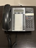 Front view of a black Mitel 5324 VOIP phone showing the digital screen, keypad, and handset.