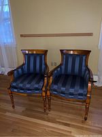Two chairs side by side on hardwood floor against wall