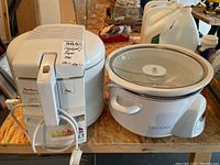 Photo showing both the Crockpot digital slow cooker on the right and the Moulinex Masterfry safe touch fryer on the left placed on wooden table.