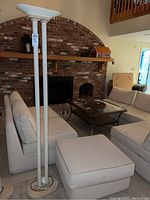 Full view of the metal and marble floor lamp showing its height and design in a living room setting.