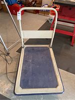 Full view of the trolley showing the foldable handle and large blue textured platform.