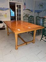 Wooden trestle kitchen table with turned legs and stretcher bars, showing entire table in room setting.