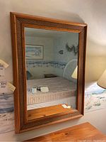 Full view of rectangular mirror showing rattan woven frame hanging on a wall above wooden furniture.