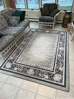 Full view of the nylon area rug showing the main design and its placement on tiled floor beside furniture.