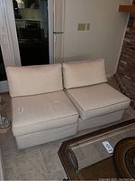 Two cream sectional chairs placed side by side, showing front and side views with cushions and piping details