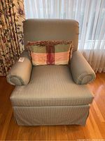 Front view of the upholstered swivel chair with striped fabric and a decorative pillow on the seat