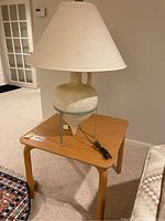 Photo showing the wood end table with the off-white textured lamp and white lampshade placed on top, showing overall size and look.