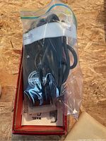 Wahl electric trimmer packed in plastic bag inside original box, black with attached cord visible.