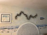 Wide shot showing all three pieces mounted on wall: framed print, decorative vine, and paddle.