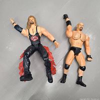 Front view of both wrestling action figures, Kevin Nash on left wearing black singlet and flame pants, Steve Austin on right in black trunks.
