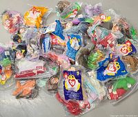 Multiple Ty Beanie Babies sealed in original McDonald's plastic polybags, showing various characters and packaging with clear brand and safety label print.