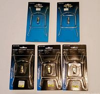 Five plate wall hangers in original packaging; two steel wire spring types and three polished brass mounts, all new and sealed by MintCraft.