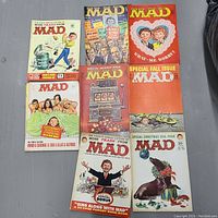 Top layout view of eight vintage MAD magazines from the 1960s with colorful illustrated covers in very good vintage condition.