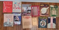 Top view of 10 music and instructional books including guitar, banjo, piano, and a Magic Eye book shown on a wooden floor.
