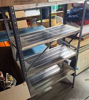 Full view of vintage metal shelving unit showing four shelves and metal frame with support braces.