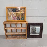 Frontal view of the framed wall art with wood textured panels, the wooden display shelf below, and the framed mirror on the right.