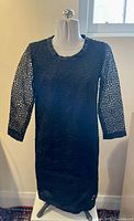 Front view of black Max Mara vintage lace dress on mannequin showing circular lace patterns, 3/4 lace sleeves, satin neckline trim