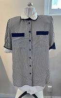 Front view of Ira Berg black and white vertically striped short sleeve button front blouse with black trim on pockets and cuffs
