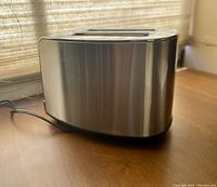 Side and top view of stainless steel toaster showing brushed metal finish surface and dual slots for bread.