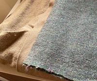 Close-up of tan wool mohair fabric and vintage textured wool fabric remnants showing fabric texture and color.
