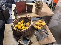 Photo showing assortment of woven baskets, wire baskets, brass-colored frames, and artificial pears arranged on wooden shelves.