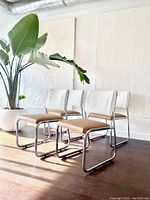 Four chrome cantilever chairs arranged together on hardwood floor.