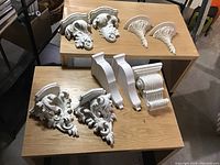 Photo showing corbels of various sizes and styles arranged on two wood surfaces, clearly showcasing differences in design and material