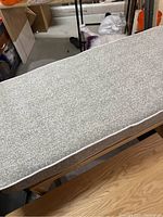 Top view of the grey rectangular bench cushion showing the speckled textured fabric and white piping around the edges.