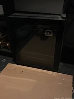 Closed view of black Igloo mini fridge with transparent glass door and logo.