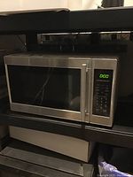 Closed Hamilton Beach microwave with stainless steel exterior and digital keypad, showing the appliance in resting state.