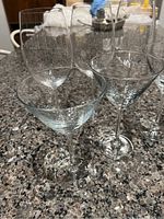 Photo showing 3 wine glasses and 3 martini glasses on a granite countertop.