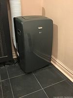 Full view of LG portable AC unit next to a wall showing vent hose attached.