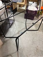 Steel tube container base frame with hollow tubing. Showing angled legs and support bars on a concrete floor with other storage items in background.