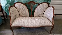 Front and full view of reupholstered Late Victorian butterfly settee with floral striped fabric and carved wooden frame.