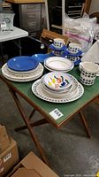 Vintage wooden folding card table with green felt surface and folding wooden legs with cross braces shown with dishware on top for scale.
