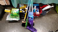 Full view of cleaning tools and supplies including mop, brooms, buckets, cleaning liquids, boxes and dustpans.