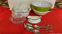 Full lot view showing Corning Ware casseroles, clear glass bowls, melamine gravy boat, and serving utensils