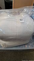 White double duvet inside clear plastic packaging, showing label and folded state.