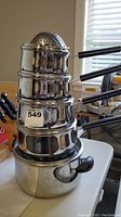 Full set of nested Lagostina stainless steel pots with handles, includes steamer insert at top.