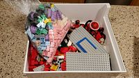 Open tray with mixed Lego and MegaBloks bricks showing various colors, wheels, and baseplates.