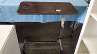 Full view of table showing steel base and wood top on wheels