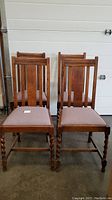 Front view of 4 vintage wooden dining chairs with re-upholstered seats and barley twist legs.