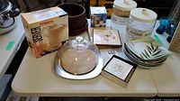 Wide view of all lot items on table showing jars, plates, bowl, coasters, and boxes
