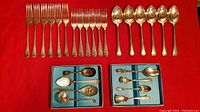 Full display of flatware including forks, spoons, and specialty serving pieces on red background