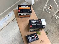 Three Duracell Ultra sealed batteries: two large 12V 35Ah and one smaller 12V 9Ah, placed on a cardboard on a concrete floor.