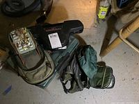 Fishing lot items grouped on floor including fishing rod and reel case, gear bag, and tackle box with lures.