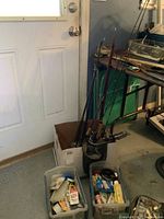 Overview of five fishing rods in box with two tackle boxes in front