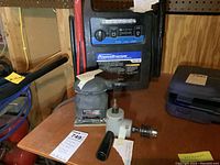 PowerStation jumpstarting unit with labels and controls visible on front panel, sitting on a wooden surface with other tools nearby.