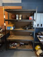 Front view of the five-tier metal shelving unit with various items on the shelves for scale, contents not included with sale.